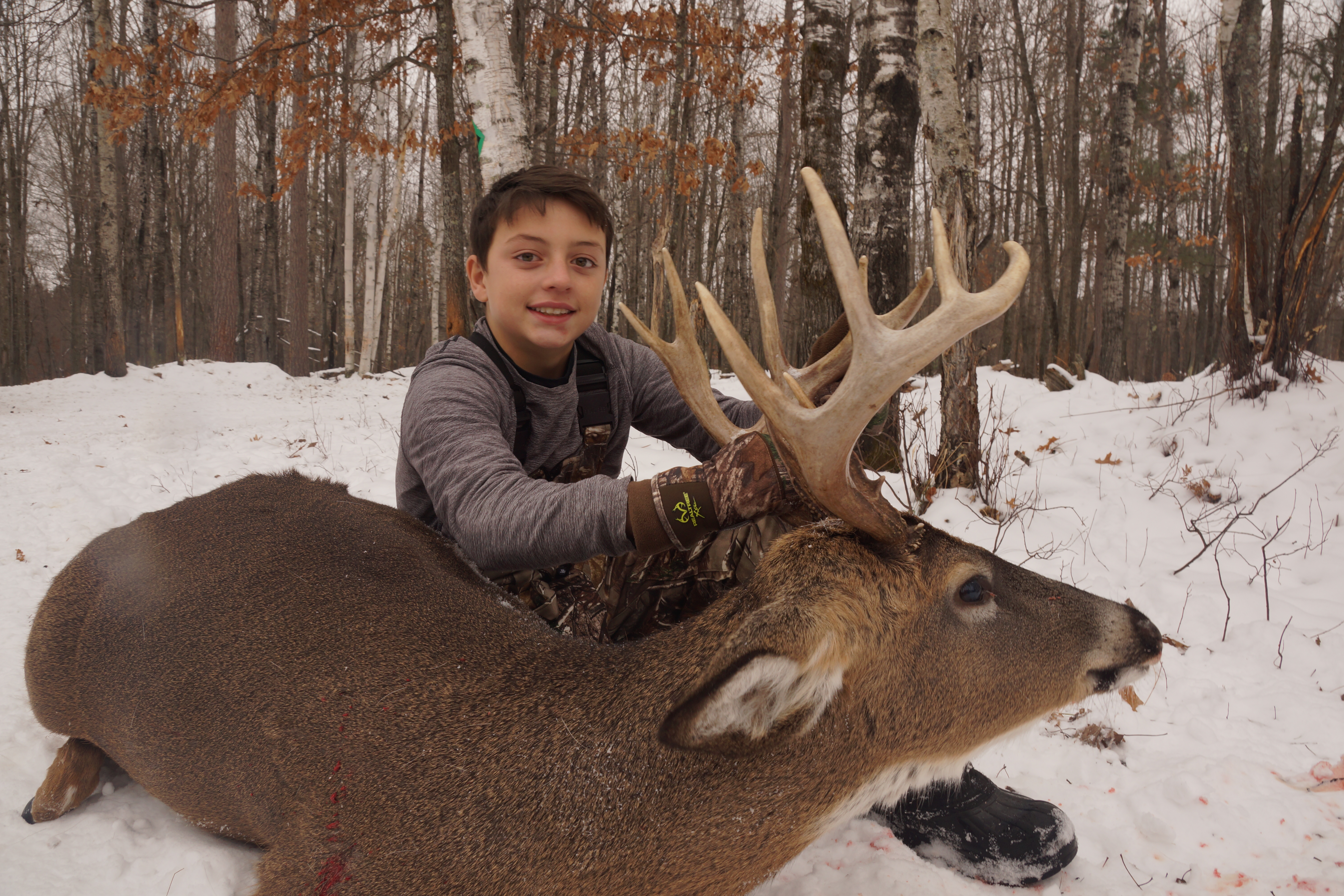 a child posing with a trophy buck after a guided hunting tour in wisconsin